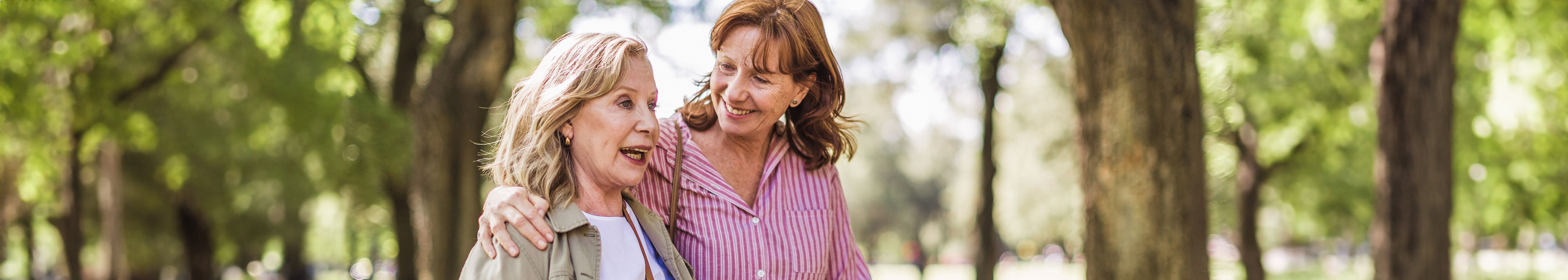 older and younger woman hug walking