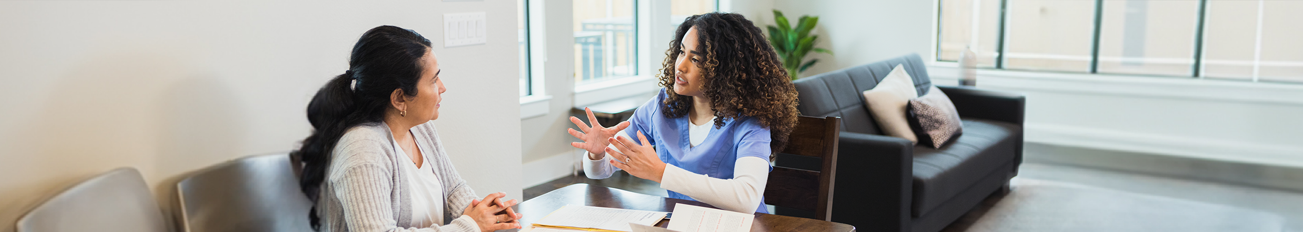 Female health professional talking to a woman across a desk, possibly about the symptoms of breast cancer